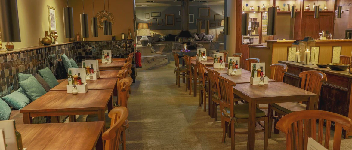 Wnętrze restauracji z&nbsp;drewnianymi stolikami i&nbsp;krzesłami, dekoracjami na&nbsp;ścianach oraz&nbsp;ciepłym, nastrojowym oświetleniem